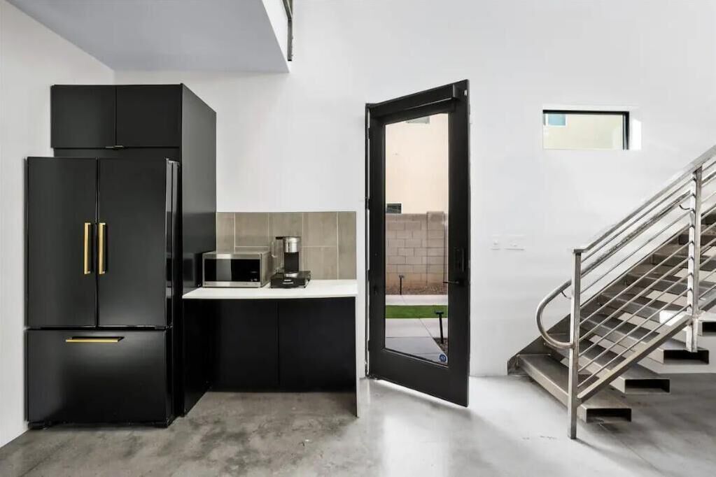 A modern kitchen with black cabinetry, a microwave, and a coffee maker.