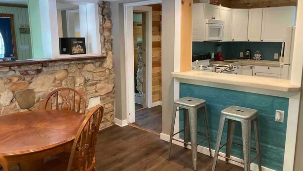 A dining area with a stone accent wall, wooden chairs, and a table.