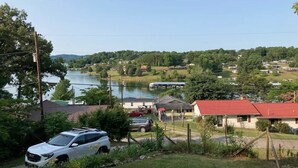 A residential area with houses, a lake, and a white SUV parked in the foreground.