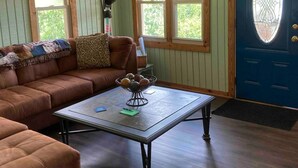 A cozy living room with a sectional sofa, a coffee table, and a blue door with a decorative glass window.