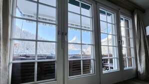 A room with large windows offering a view of snow-covered trees and mountains. - Haus Vira (Zermatt)