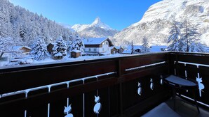 A snow-covered mountain landscape with a chalet-style building in the foreground and a prominent mountain peak in the background. - Haus Vira (Zermatt)