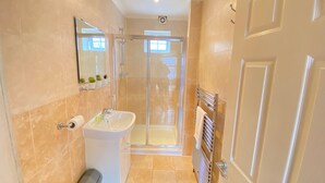 A modern bathroom with a glass-enclosed shower, a white sink, and a towel rack. - Stunning 1-bed Apartment in London (London)