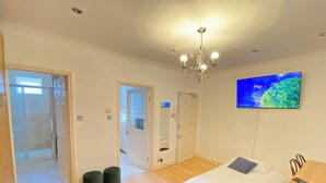 A hotel room with two beds, a TV, a chandelier, and a door leading to a balcony. - Stunning 1-bed Apartment in London (London)