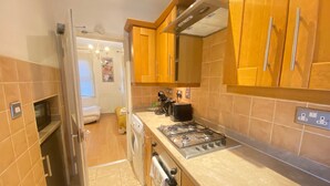 A compact kitchen with wooden cabinets, a gas stove, a microwave, and a built-in oven. - Stunning 1-bed Apartment in London (London)