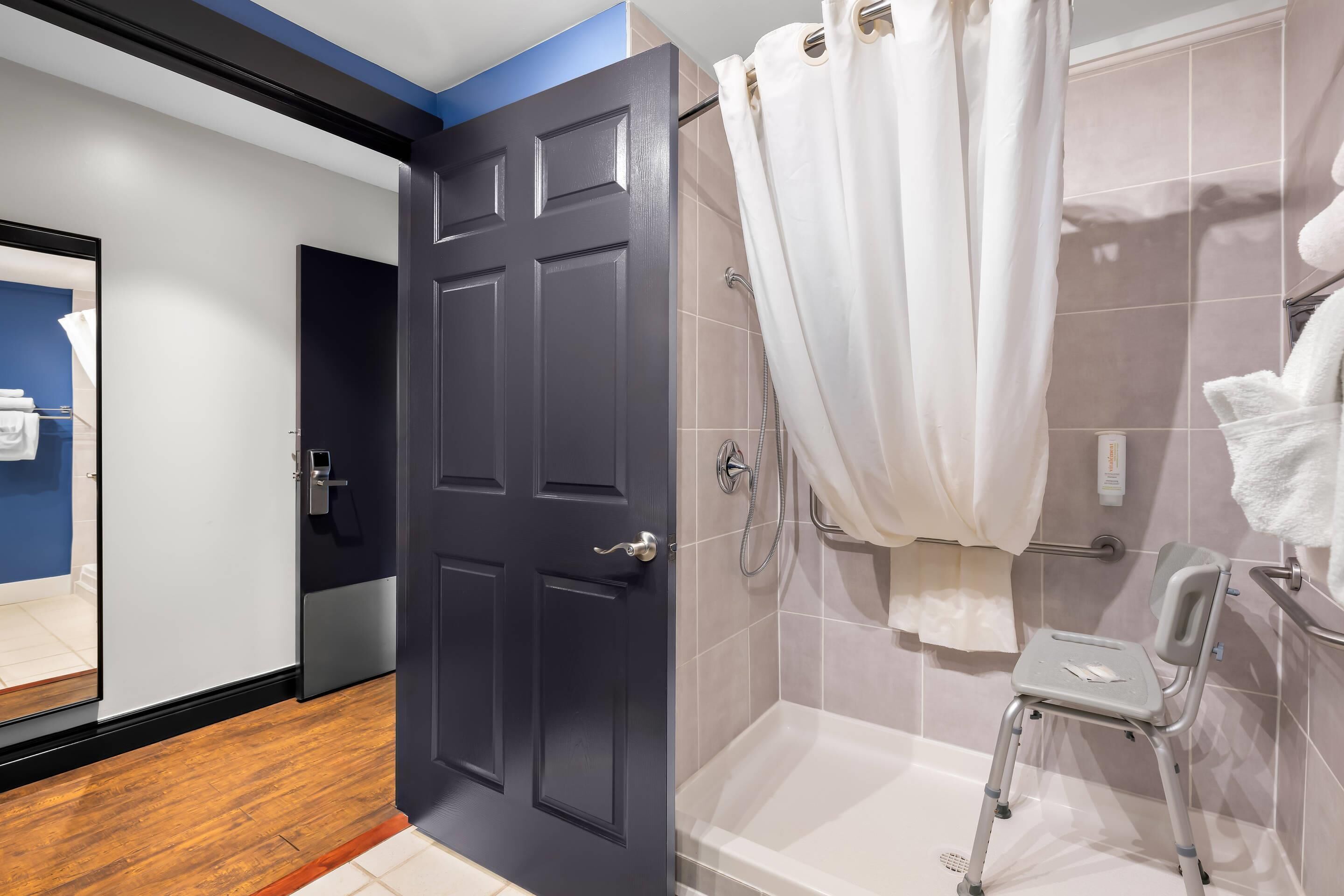 Un baño moderno con ducha, inodoro y un pequeño taburete.