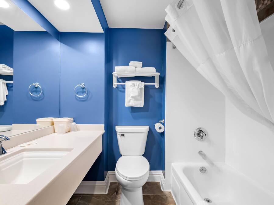 Un baño moderno con una pared azul de acento, un lavamanos blanco, un inodoro y una bañera.