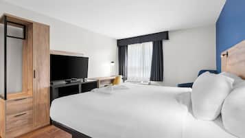 Une chambre d’hôtel avec un grand lit, un bureau doté d’un téléviseur à écran plat, une armoire et une fenêtre avec des rideaux.
