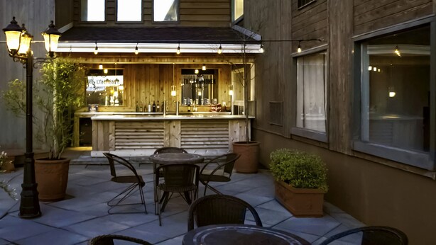 An outdoor bar area with wooden furniture, potted plants, and string lights. - Park Inn - by Choice Hotels, Sydney (Sydney)