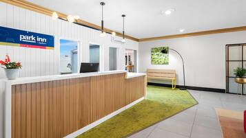 Un mostrador de recepción con el letrero 'Park Inn', una computadora y un banco.
