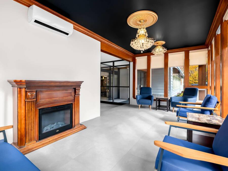 Una sala de estar moderna con chimenea, sillones azules, una araña y ventanas grandes.