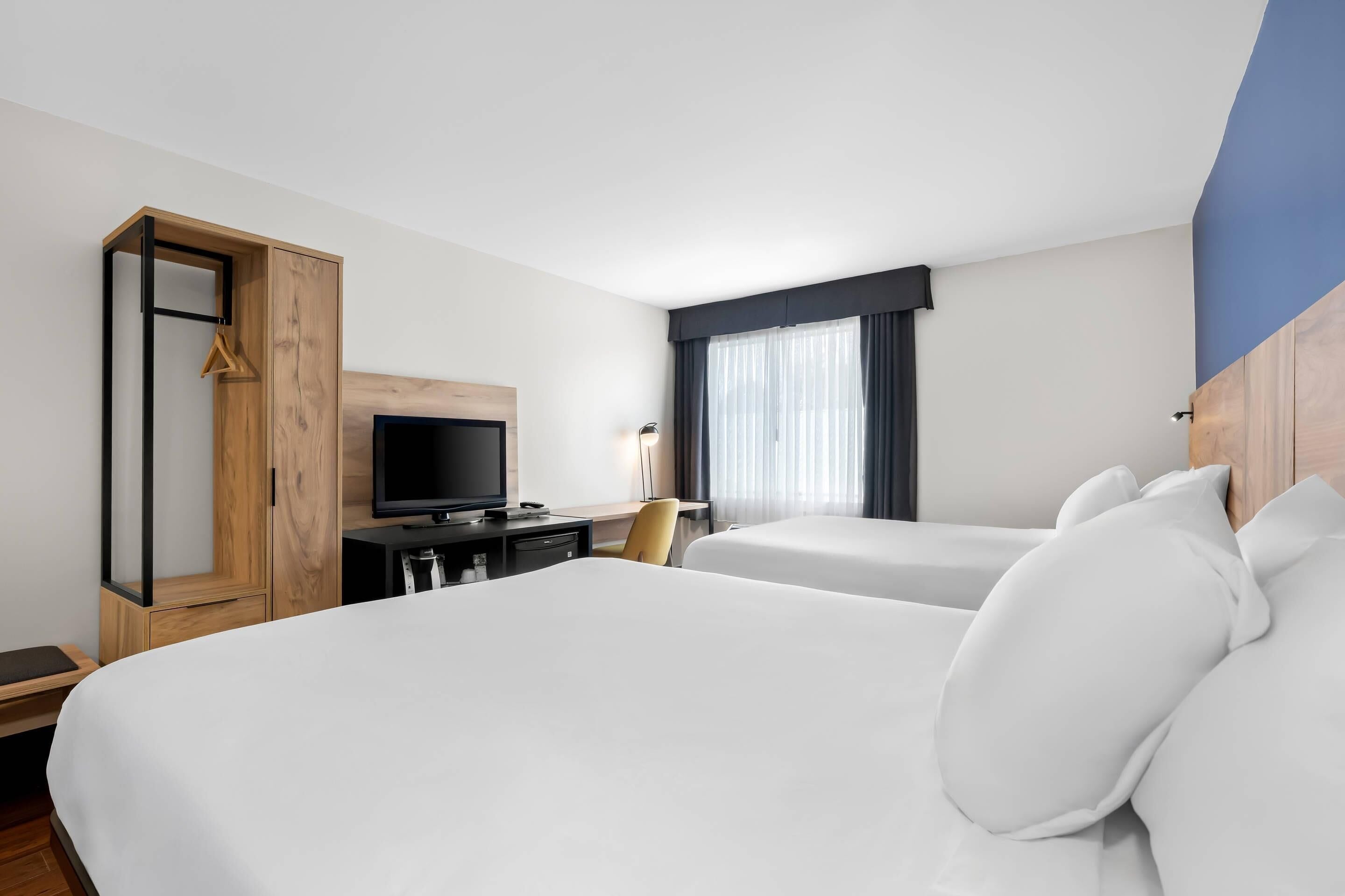 Une chambre d’hôtel avec deux lits, une télévision, un bureau et une armoire.