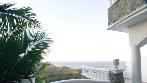 Un balcon doté d’une balustrade blanche, d’où l’on peut admirer un paysage côtier.