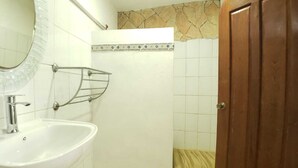 Une salle de bain avec un lavabo, un miroir, une douche et une porte en bois.