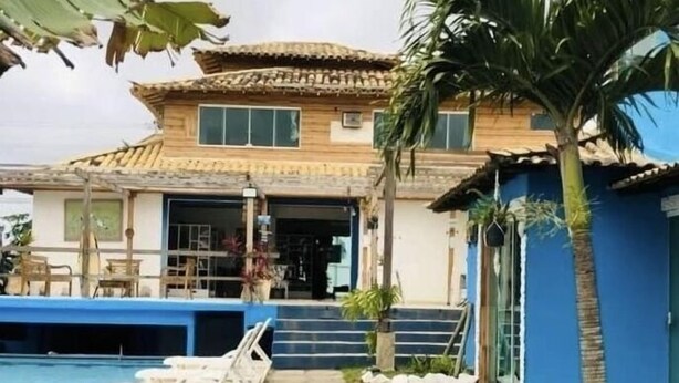 Une maison à deux étages avec une piscine, un patio couvert et un palmier.