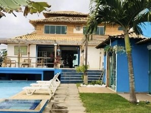 Et toetagers hus med swimmingpool, overdækket terrasse og en palme.