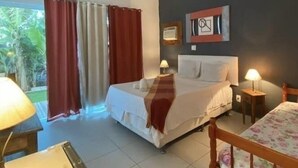 Une chambre d’hôtel comprenant un lit, deux tables de chevet avec des lampes, une fenêtre avec des rideaux et un tableau accroché au mur.