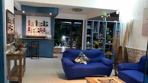 Un vaste espace de vie comprenant deux canapés bleus, une table basse en bois et un coin cuisine avec un bar et des étagères.