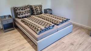 A modern bedroom with a bed, two nightstands, and a small bedside table with a lamp.