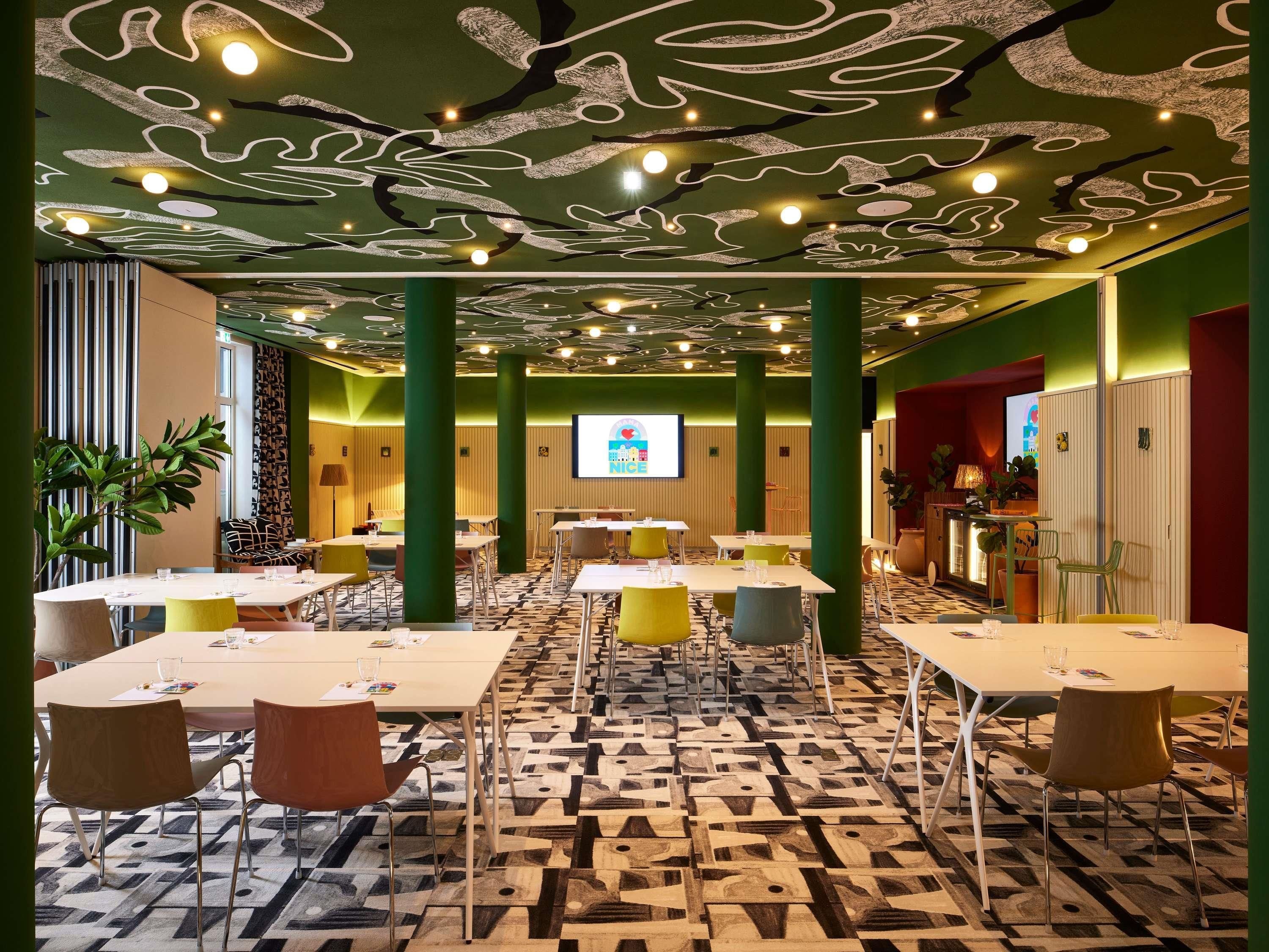 Un salón de conferencias con mesas, sillas y una pantalla de proyección.