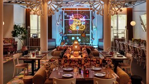 A spacious dining area with a long table set for multiple guests, surrounded by comfortable seating. - Mama Shelter Nice (Nice)