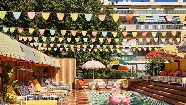 A pool area with colorful triangular flags, sun loungers, and inflatable pool toys. - Mama Shelter Nice (Nice)