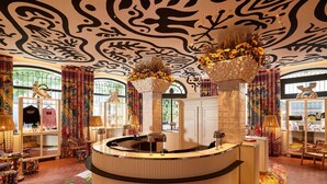 A circular reception desk with a patterned carpet, a decorative ceiling, and a window with a view. - Mama Shelter Nice (Nice)