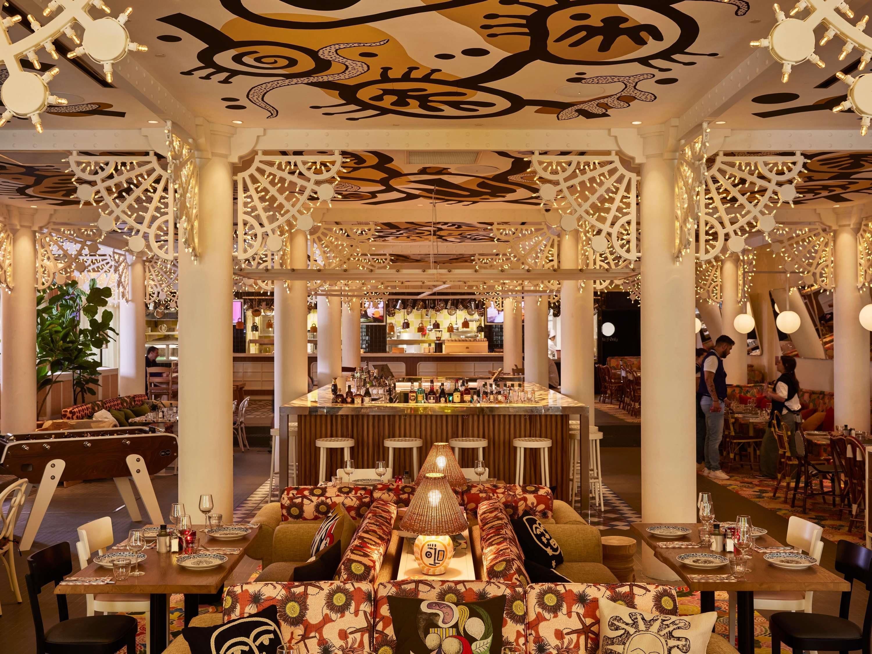 Un restaurante con zona de bar, cabinas y techo con diseño.