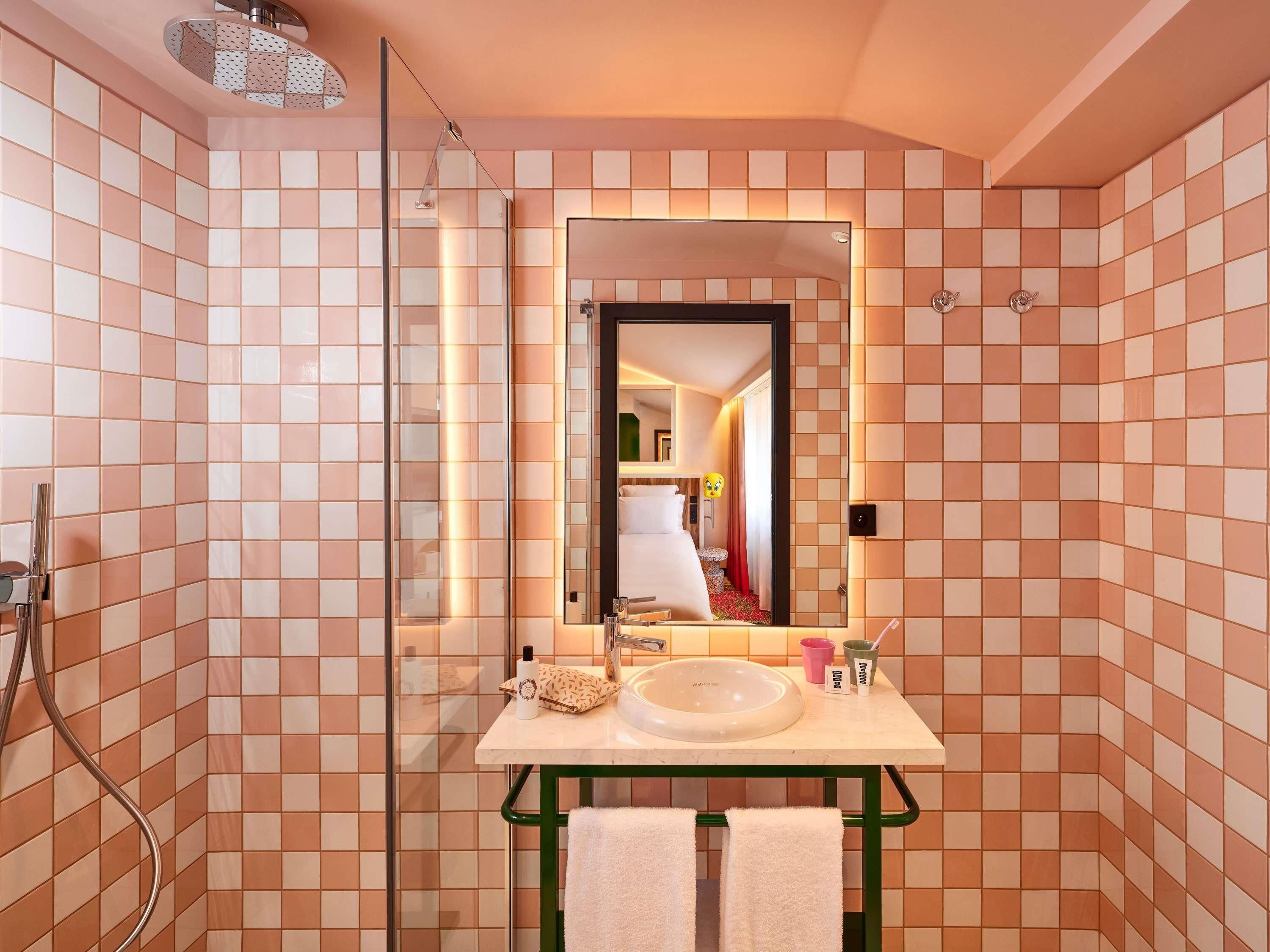 Un baño con cabina de ducha de vidrio, un lavabo con espejo y un perchero para toallas.