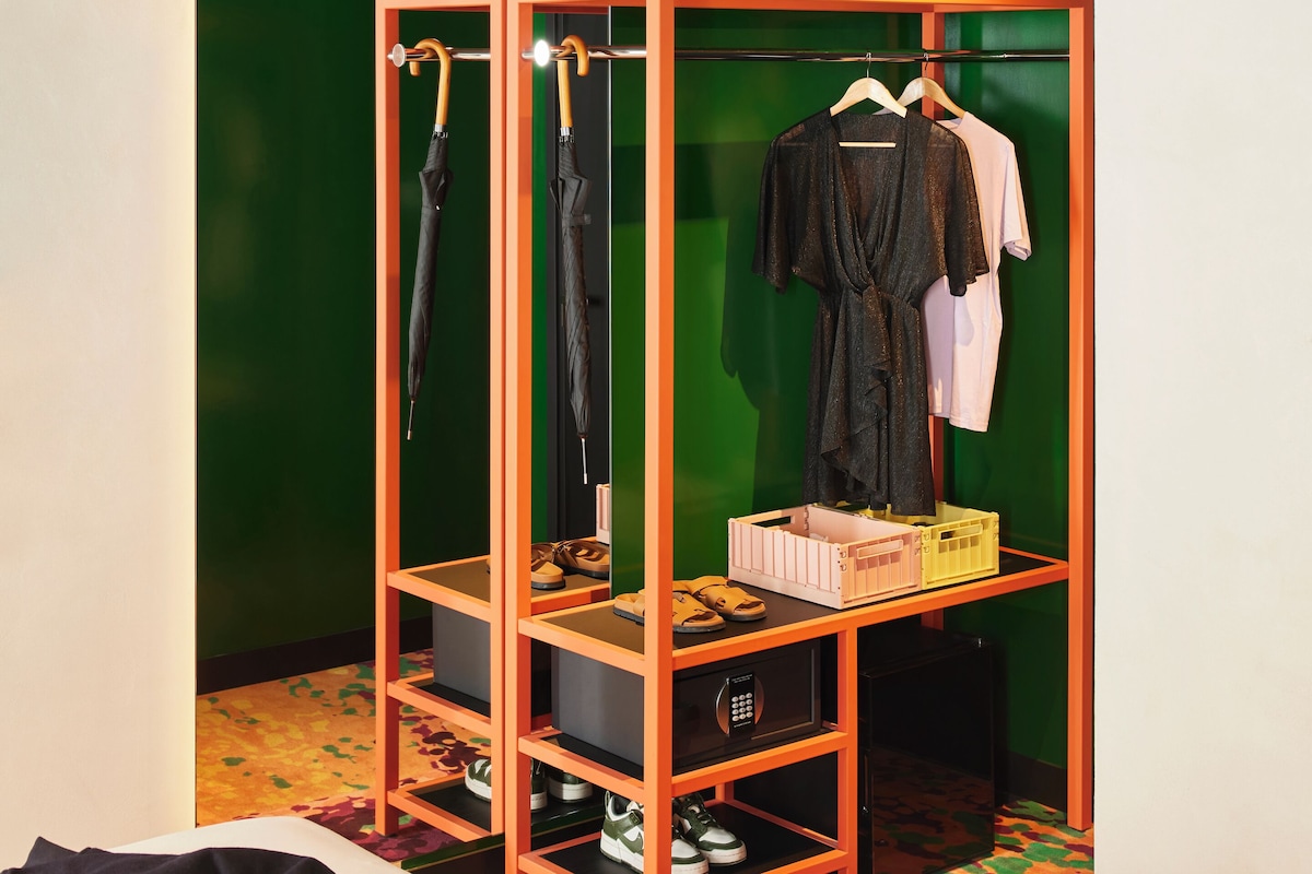 Quarto com parede verde, guarda-roupa de madeira com espelho e cama com tapete colorido.