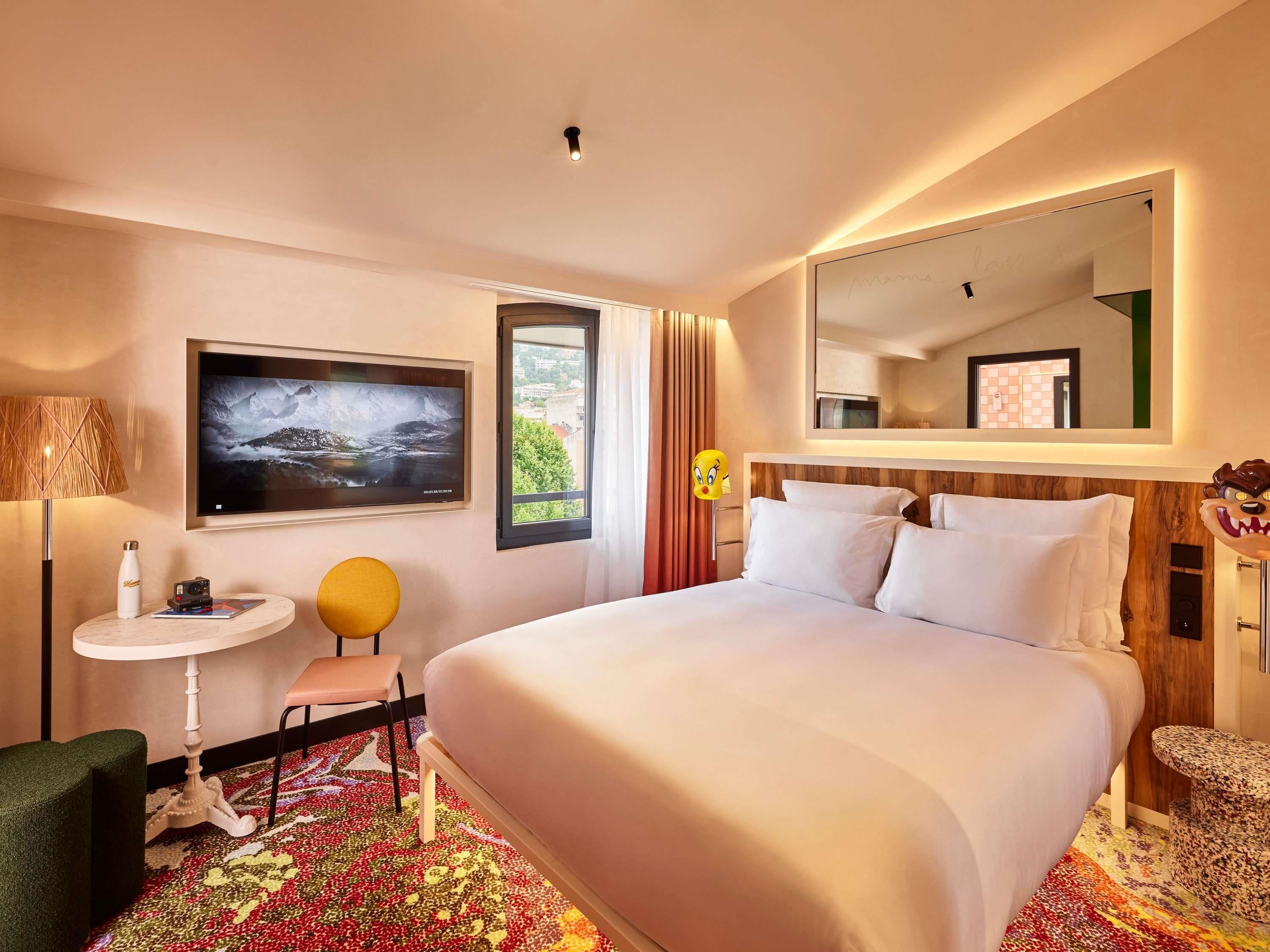 Habitación de hotel con una cama grande, televisión, una mesita y una silla.