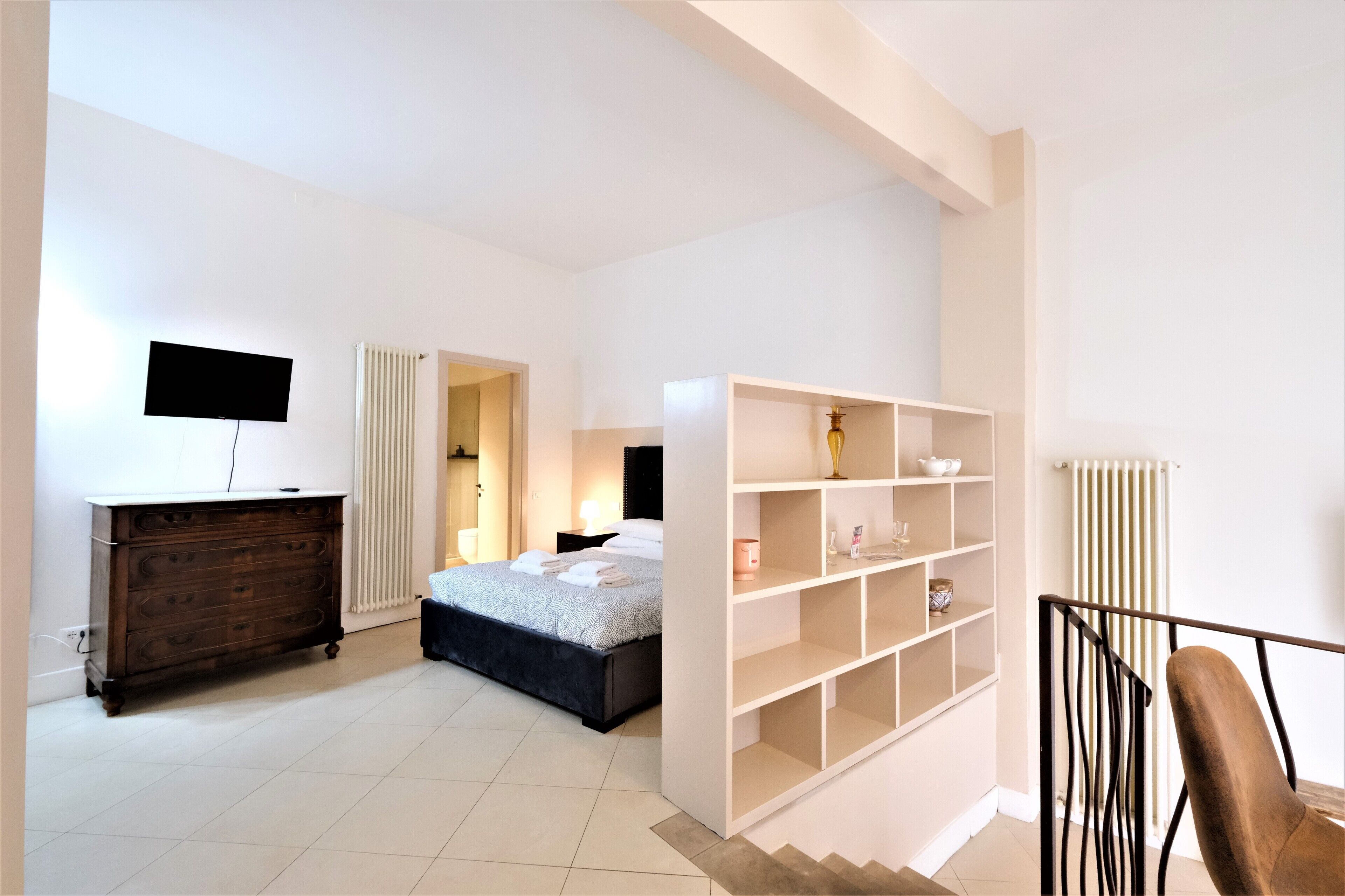 A bedroom with a bed, dresser, TV, and built-in shelving.