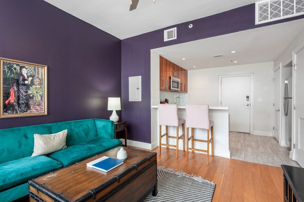 A modern living room with a green sofa, a wooden coffee table, and a painting on the wall.