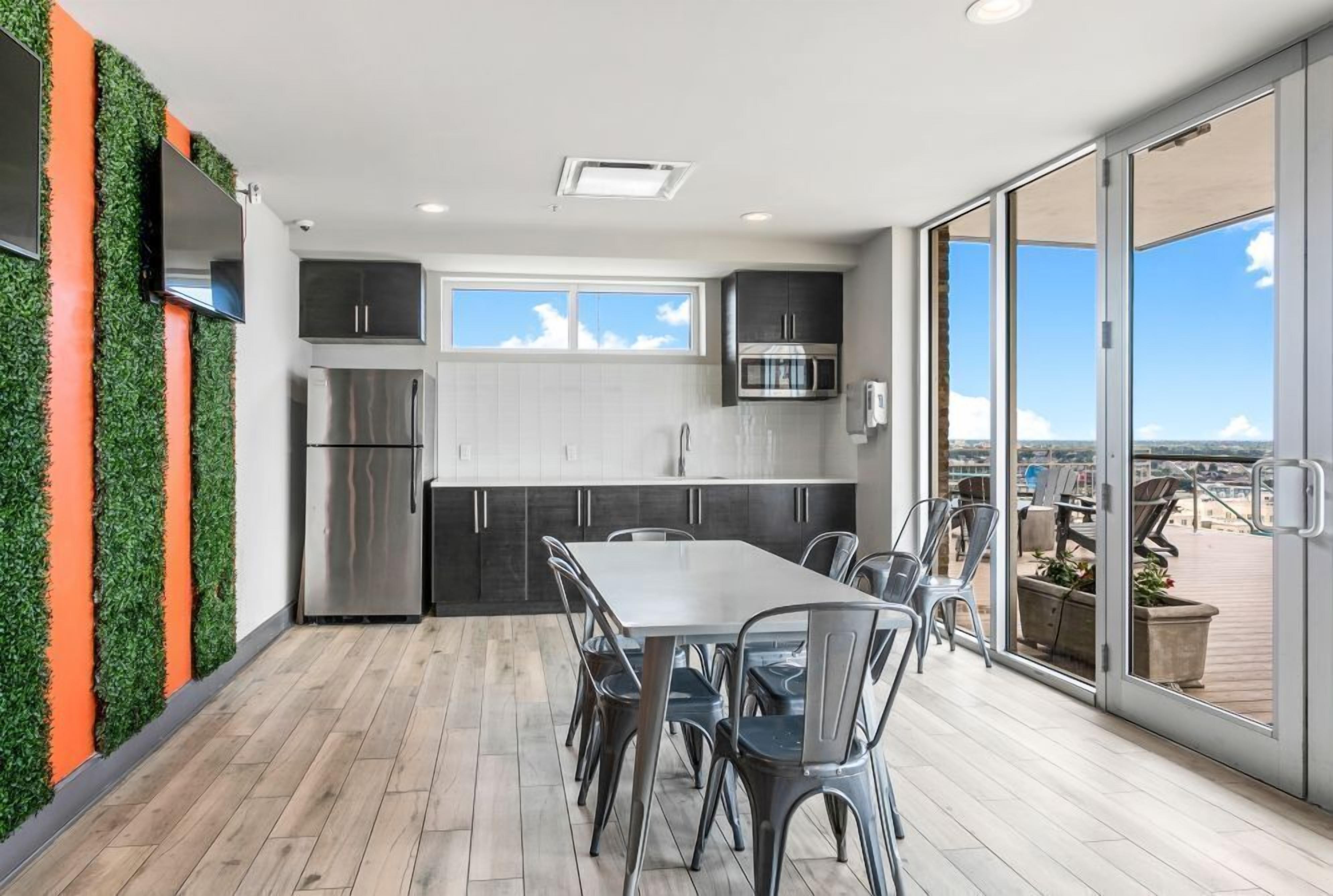 A modern kitchen with stainless steel appliances, a dining area with a table and chairs, and a large sliding glass door leading to an outdoor deck.