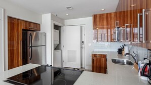 Une cuisine moderne dotée d’une cuisinière intégrée, d’appareils électroménagers en acier inoxydable et de meubles de rangement en bois.