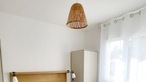 A neatly arranged hotel room with a bed, a wardrobe, a bedside lamp, and a window with curtains.