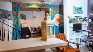 Une pièce comprenant un coin repas, un téléviseur et une bibliothèque remplie de livres et de magazines.