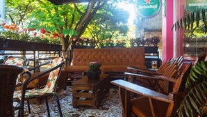 Un espace extérieur aménagé avec des meubles en osier, un canapé capitonné et une enseigne Heineken.