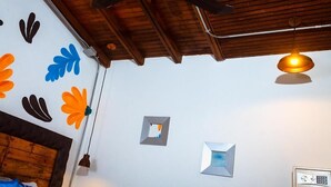 Un ventilateur de plafond, un luminaire suspendu et des décorations murales aux motifs floraux.