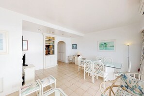 A spacious living area with a dining table, chairs, a bookshelf, and a TV.