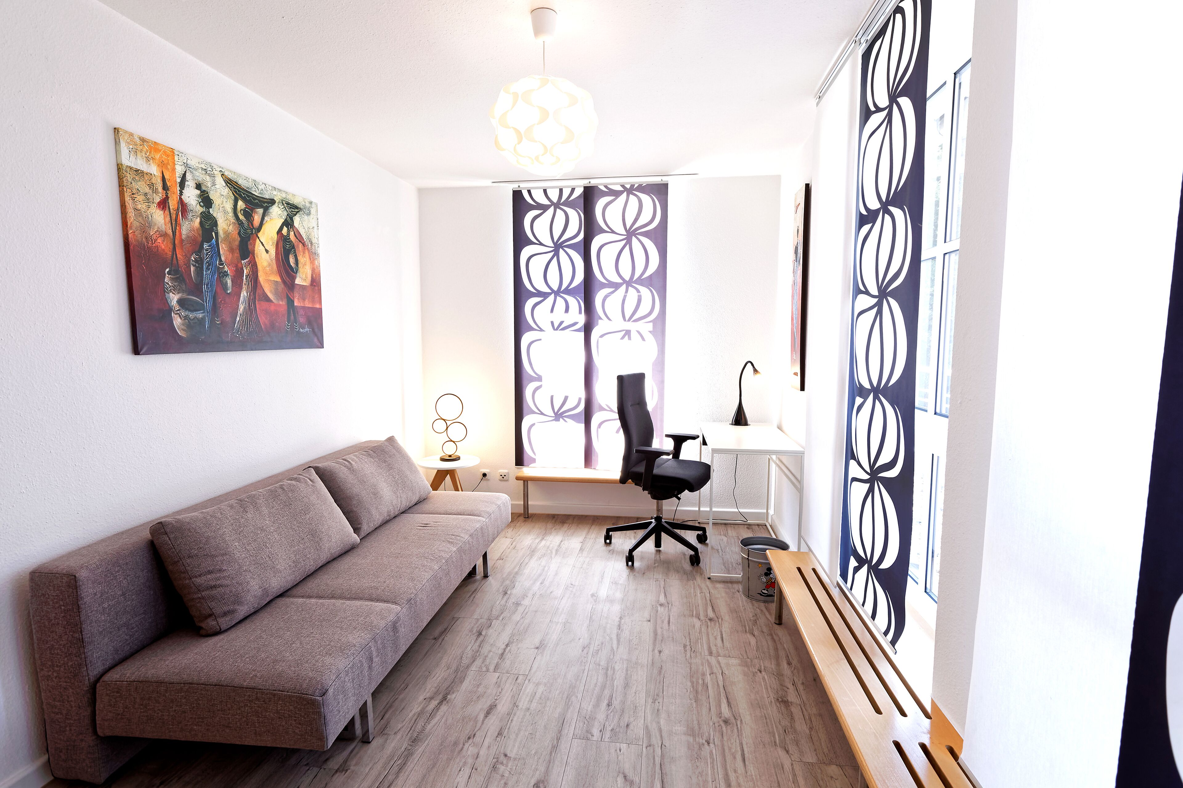 A modern living room with a sofa, a desk, and a chair.