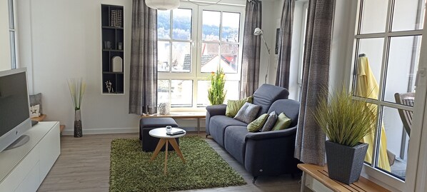 Un salon moderne avec un canapé, une table basse et un téléviseur posé sur un meuble.