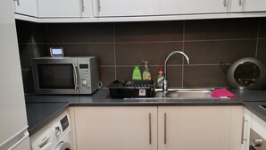 Cocina compacta con lavadora, microondas y lavabo.