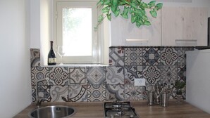 A kitchen with a window, a sink, a stove, and decorative tiles. - 2 Bedroom Apartment in Sambuca di Sicilia (Sambuca di Sicilia)