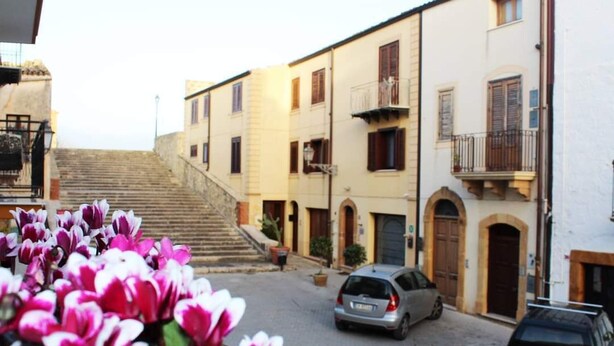A street with buildings, a car, and flowers. - 2 Bedroom Apartment in Sambuca di Sicilia (Sambuca di Sicilia)