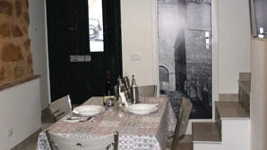 A dining area with a table set for two, a wine bottle, and a view of a building through a glass door. - 2 Bedroom Apartment in Sambuca di Sicilia (Sambuca di Sicilia)