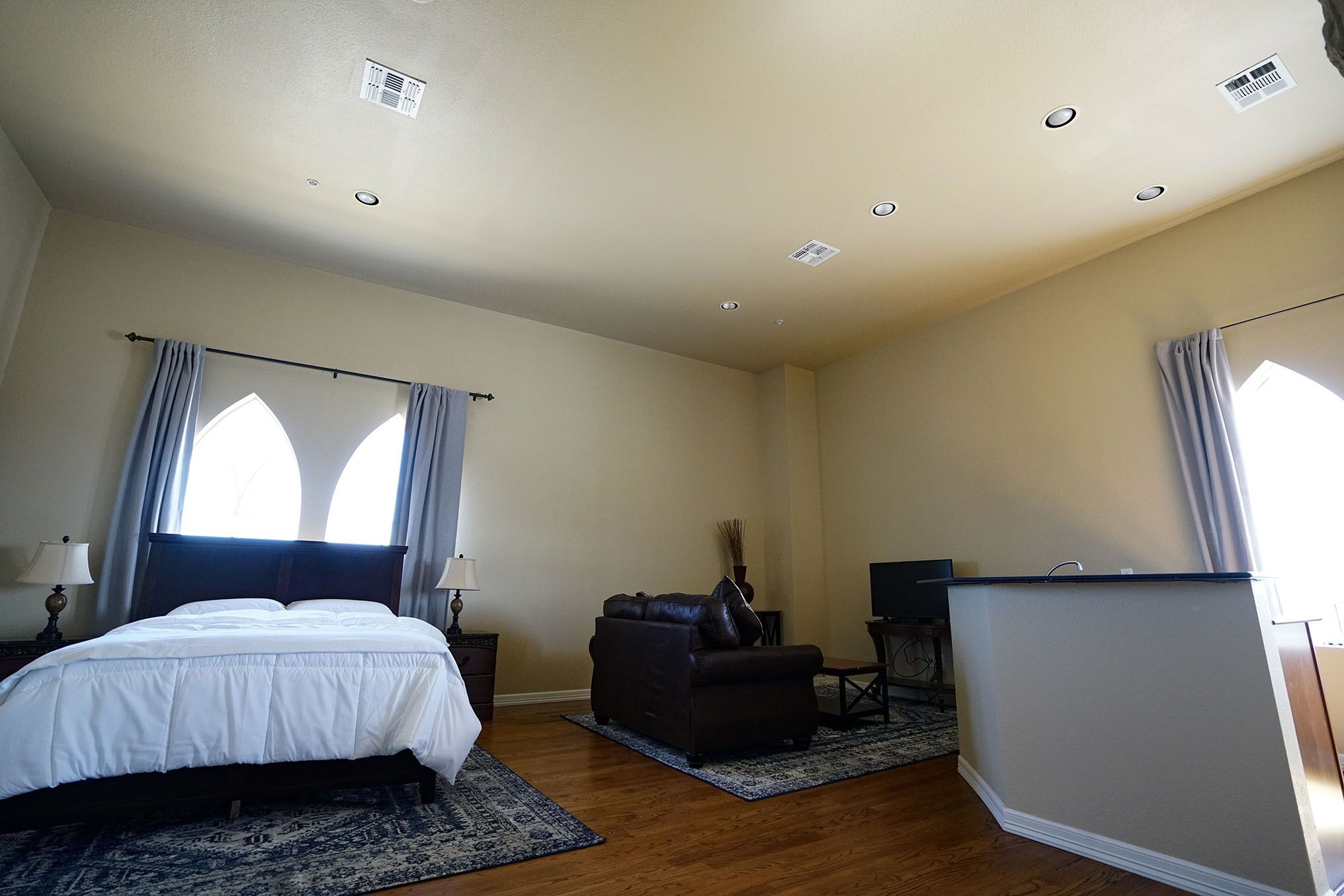 Quarto com cama, escrivaninha, cadeira e janela com cortinas.