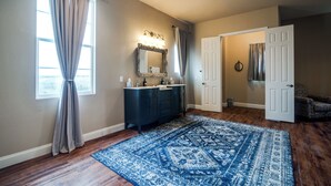 A bathroom with a vanity, mirror, and a blue patterned rug.