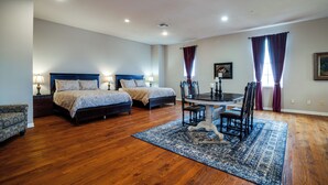 A bedroom with two beds, a dining table with chairs, and a patterned rug.