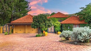 A courtyard with a paved walkway, surrounded by buildings with red-tiled roofs and yellow walls.